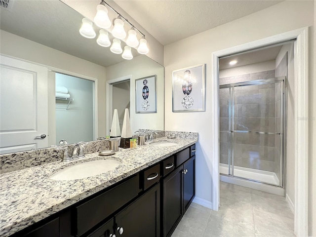 bathroom with tile patterned floors, vanity, a textured ceiling, and walk in shower