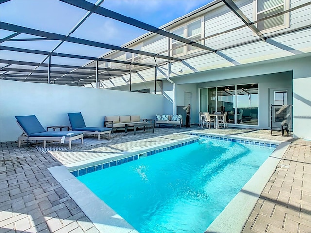 view of swimming pool featuring outdoor lounge area, a patio, and glass enclosure