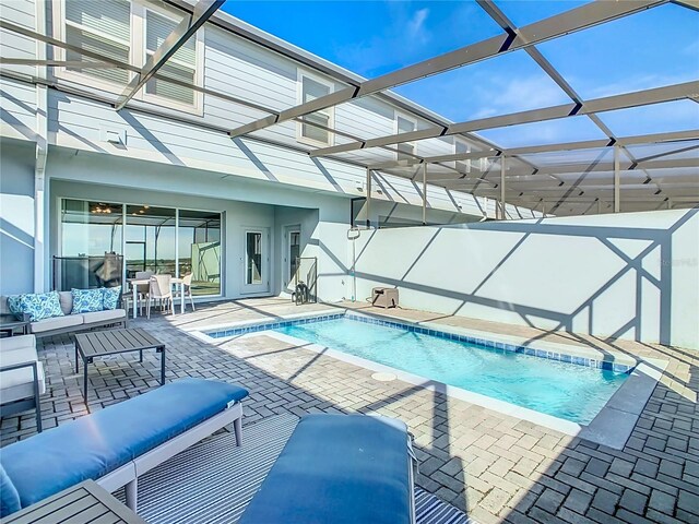 view of pool with outdoor lounge area, a jacuzzi, a patio area, and a lanai