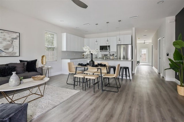 dining area with ceiling fan and light wood-type flooring