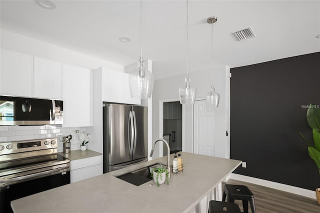 kitchen with sink, white cabinets, hanging light fixtures, and appliances with stainless steel finishes