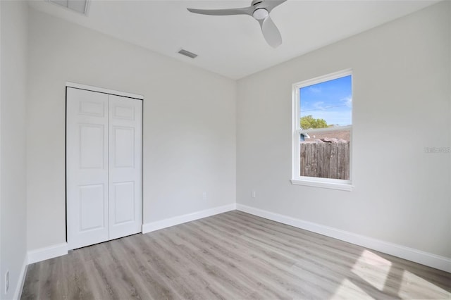 unfurnished bedroom with ceiling fan, light wood-type flooring, and a closet