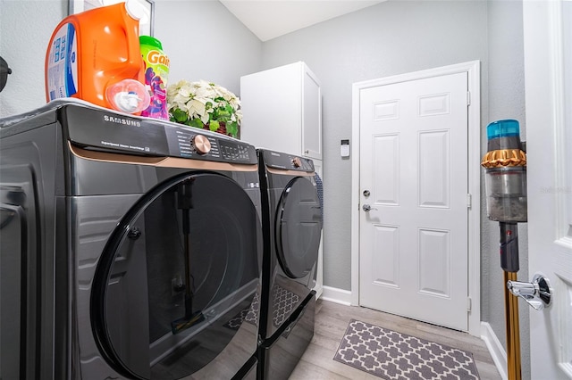 washroom featuring cabinets, light hardwood / wood-style flooring, and washer and clothes dryer