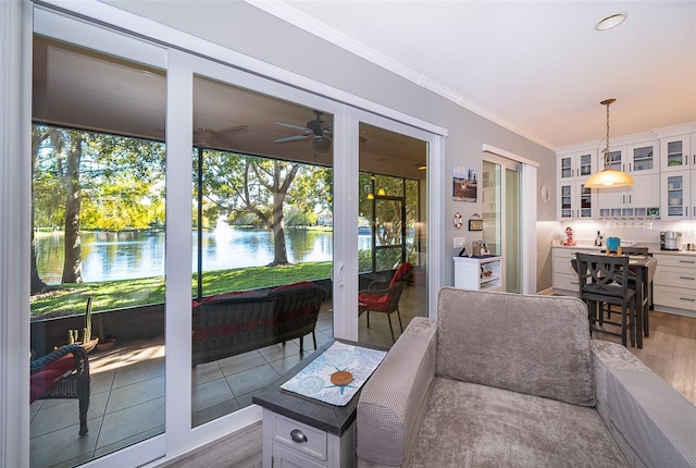 living room with ceiling fan, a water view, wood-type flooring, and crown molding