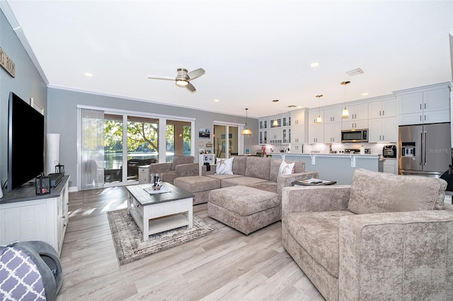 living room with light wood-type flooring, ceiling fan, and crown molding