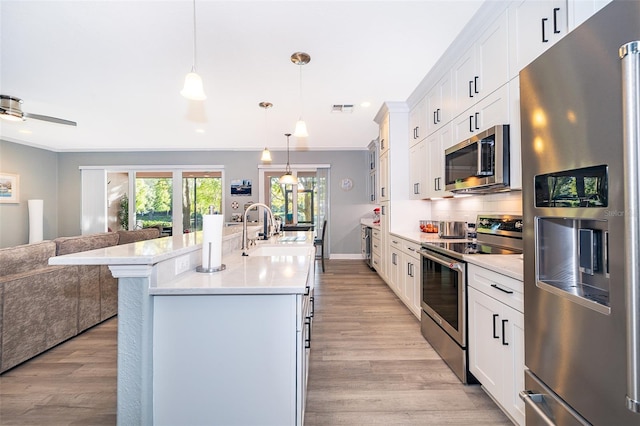 kitchen with sink, hanging light fixtures, light hardwood / wood-style flooring, white cabinetry, and stainless steel appliances