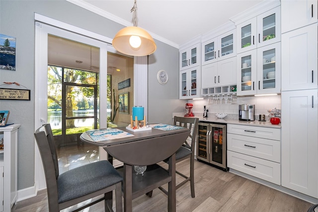 dining room featuring crown molding, beverage cooler, and light wood-type flooring