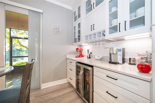 kitchen featuring decorative backsplash, light wood-type flooring, beverage cooler, crown molding, and white cabinets