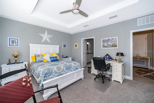 bedroom with ceiling fan, crown molding, connected bathroom, and a tray ceiling