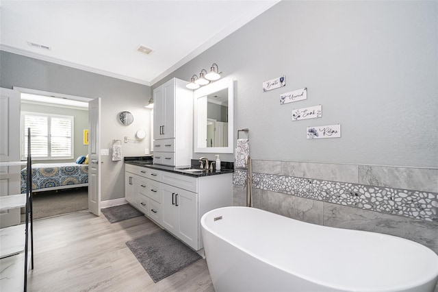 bathroom with hardwood / wood-style floors, vanity, crown molding, and a tub to relax in