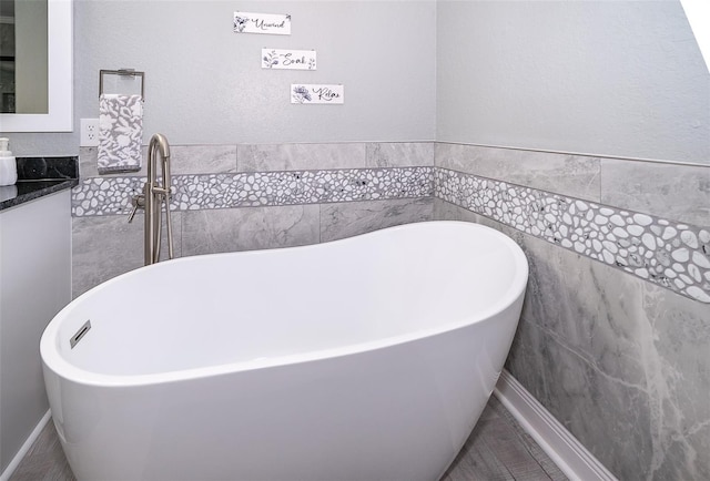 bathroom featuring vanity, tile walls, and a tub