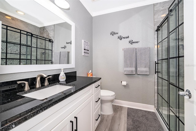 bathroom with vanity, crown molding, tiled shower, wood-type flooring, and toilet