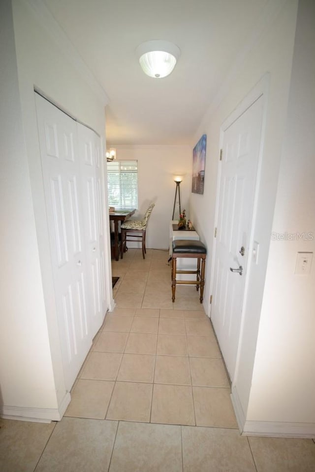 hall with light tile patterned flooring and crown molding