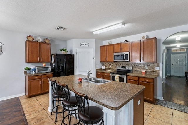 kitchen featuring a kitchen island with sink, sink, stainless steel appliances, and light hardwood / wood-style flooring