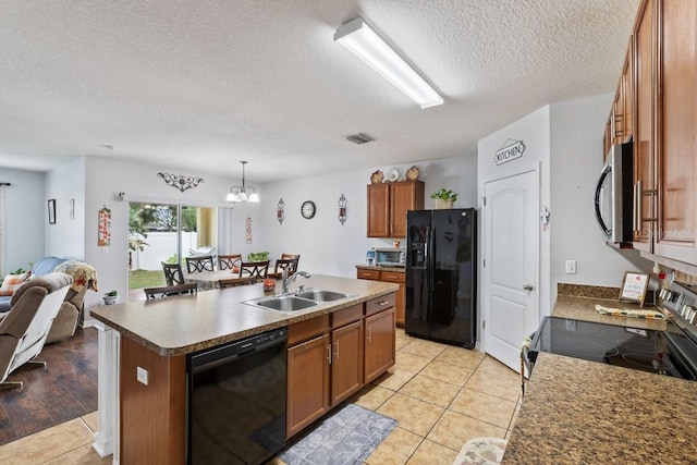 kitchen featuring sink, black appliances, pendant lighting, a center island with sink, and a chandelier