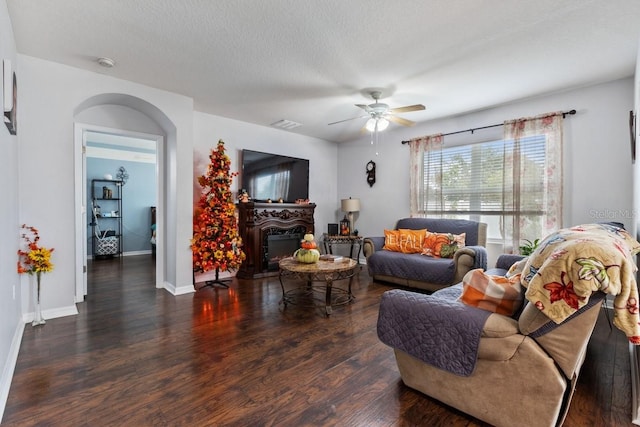 living room with ceiling fan, dark hardwood / wood-style flooring, and a textured ceiling