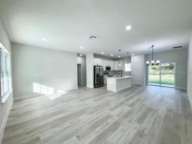 kitchen with white cabinetry, sink, stainless steel appliances, pendant lighting, and light hardwood / wood-style floors