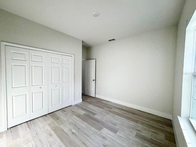 unfurnished bedroom with vaulted ceiling, light wood-type flooring, and a closet