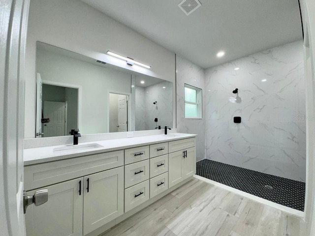 bathroom featuring hardwood / wood-style floors, vanity, and tiled shower