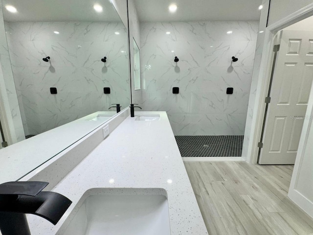 bathroom with tiled shower, hardwood / wood-style floors, and vanity