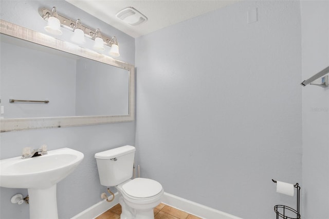 bathroom with toilet, tile patterned floors, and sink