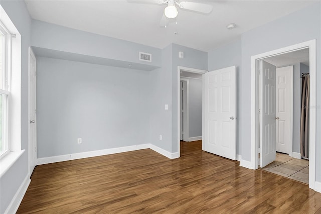 unfurnished bedroom with multiple windows, hardwood / wood-style floors, and ceiling fan