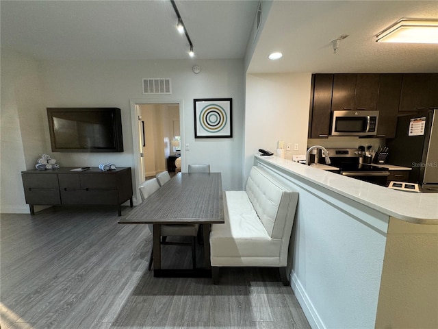 dining area with rail lighting, hardwood / wood-style flooring, and sink