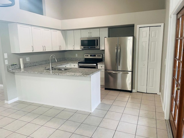 kitchen with light stone counters, kitchen peninsula, sink, and appliances with stainless steel finishes