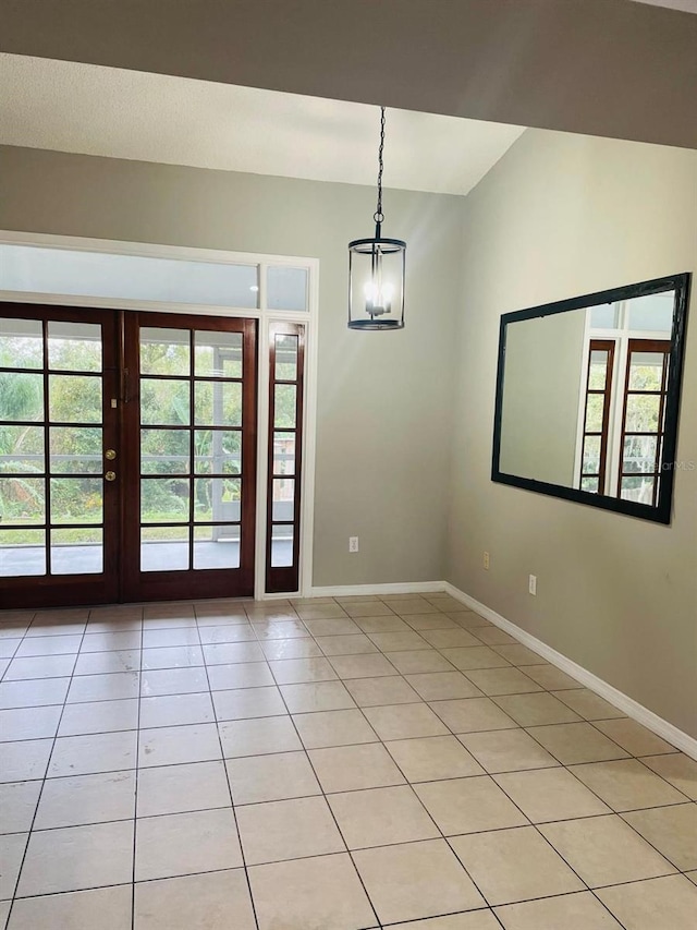 tiled empty room with a chandelier and french doors