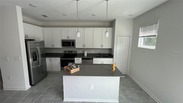 kitchen featuring pendant lighting, white cabinets, sink, appliances with stainless steel finishes, and a kitchen island