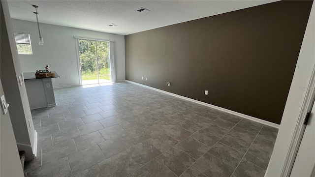 spare room featuring a textured ceiling and dark tile patterned flooring