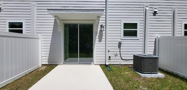 view of exterior entry with a patio area and central air condition unit