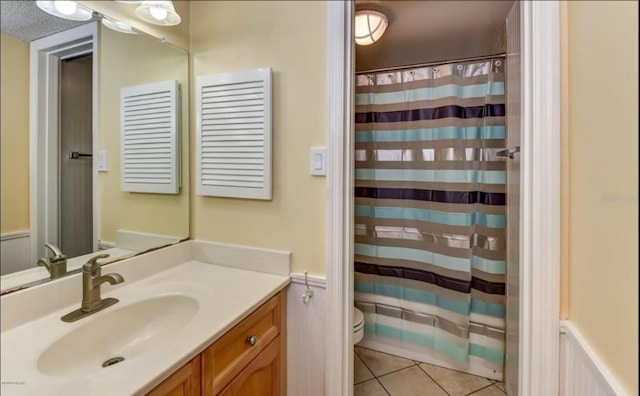 bathroom with tile patterned flooring, vanity, a textured ceiling, and toilet