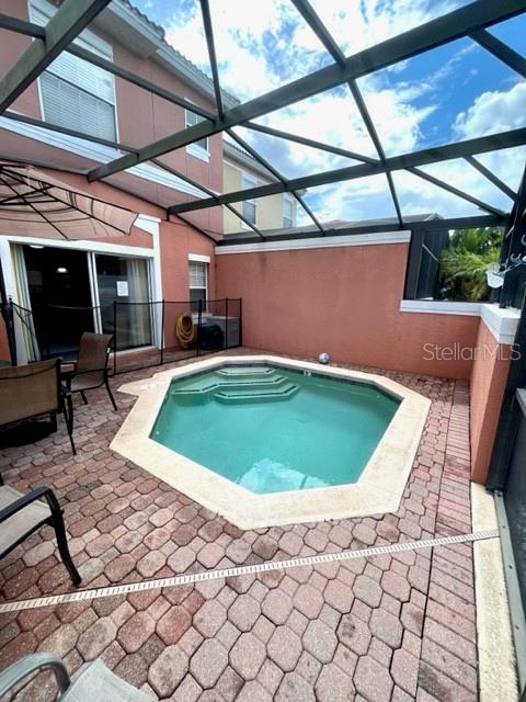 view of swimming pool with glass enclosure and a patio