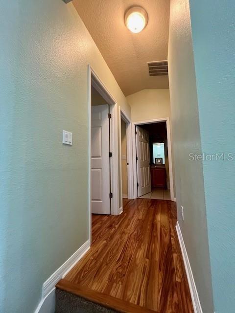 hall featuring wood-type flooring and lofted ceiling