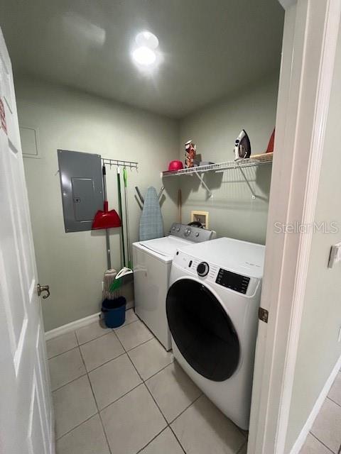 washroom with washer and dryer, light tile patterned floors, and electric panel