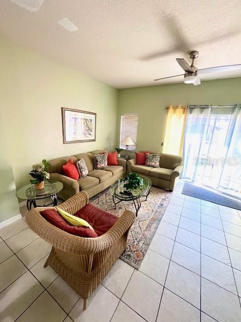 tiled living room with a textured ceiling and ceiling fan