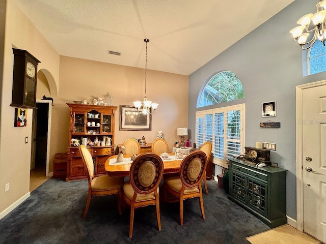 dining area featuring dark colored carpet, high vaulted ceiling, and an inviting chandelier