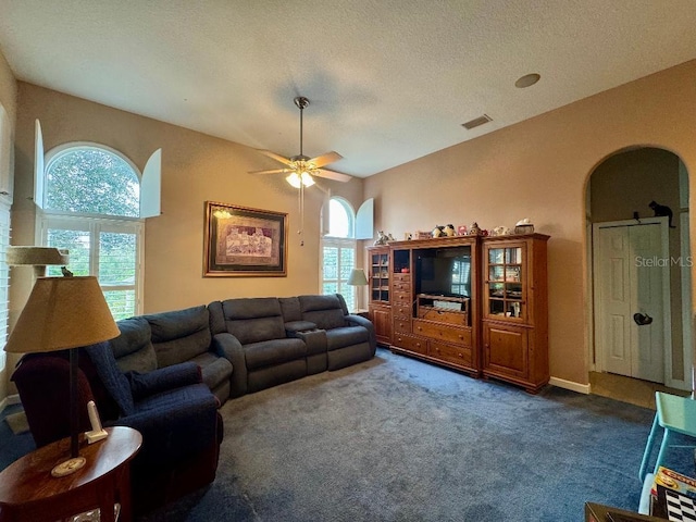 living room with ceiling fan, dark carpet, and a textured ceiling