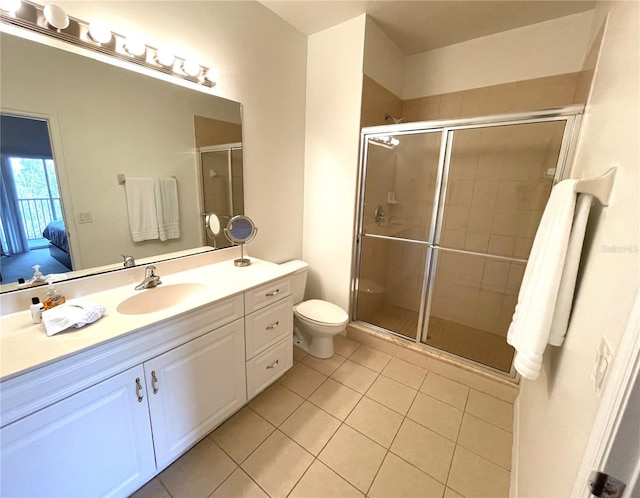 bathroom featuring toilet, vanity, tile patterned floors, and a shower with shower door