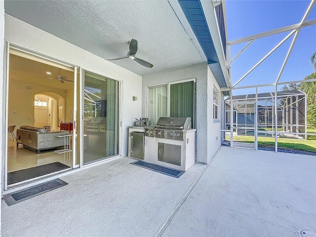 view of patio featuring a grill, ceiling fan, glass enclosure, and exterior kitchen