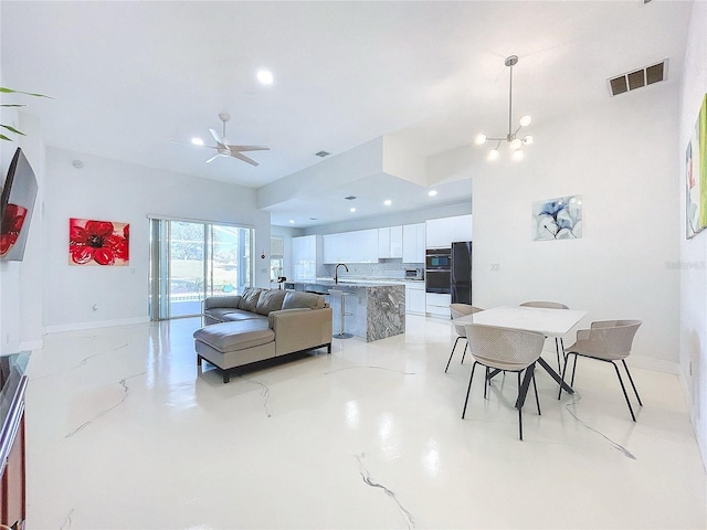 dining room with ceiling fan with notable chandelier and sink