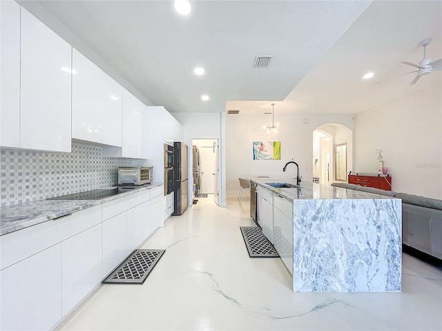 kitchen featuring pendant lighting, backsplash, ceiling fan with notable chandelier, sink, and white cabinetry