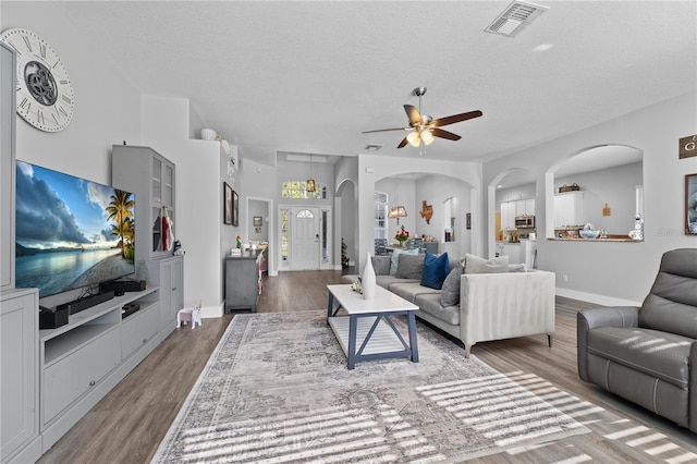 living room featuring ceiling fan, hardwood / wood-style floors, and a textured ceiling