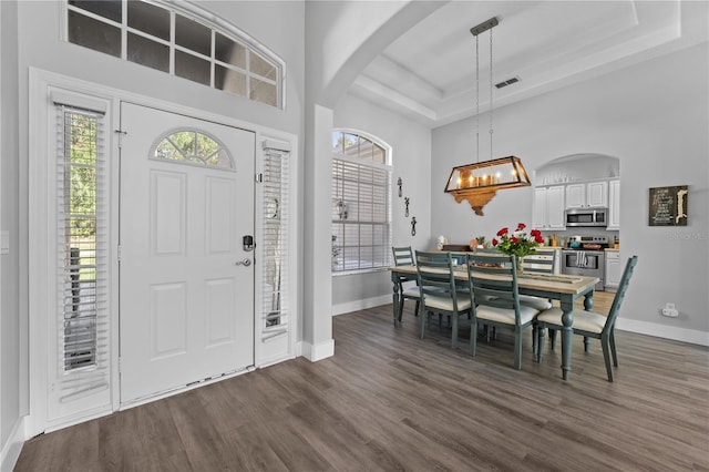 entryway with dark hardwood / wood-style flooring, a raised ceiling, and a notable chandelier