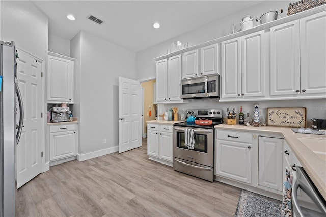 kitchen featuring white cabinets, light wood-type flooring, and stainless steel appliances