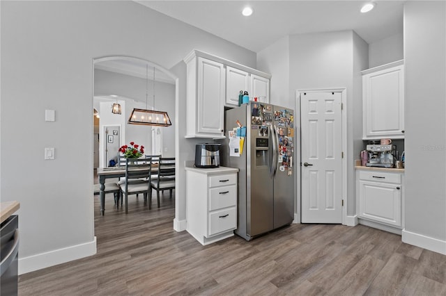 kitchen with white cabinets, hanging light fixtures, appliances with stainless steel finishes, and light hardwood / wood-style flooring