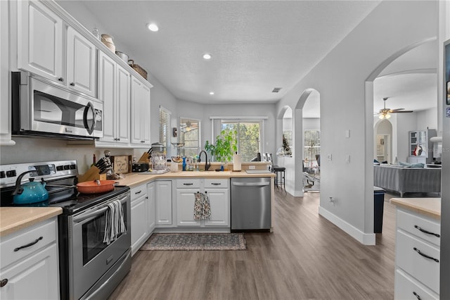 kitchen featuring white cabinets, ceiling fan, wood-type flooring, and appliances with stainless steel finishes