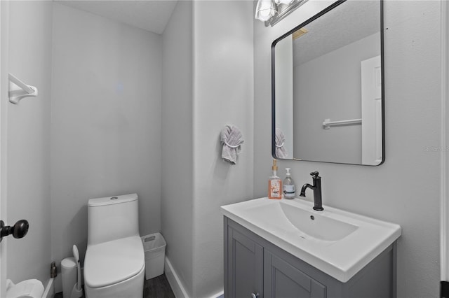 bathroom with vanity, toilet, and a textured ceiling