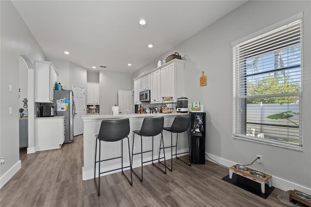 kitchen featuring white cabinetry, a kitchen bar, kitchen peninsula, and appliances with stainless steel finishes